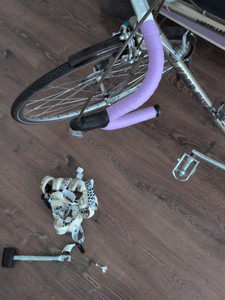 Photo of a bicycle handlebar from above. It is a drop bar wrapped in some lavender textile tape, with black handlebar plugs. The remaining frame of the bike has a not-very-shiny, somewhat tinted golden color.